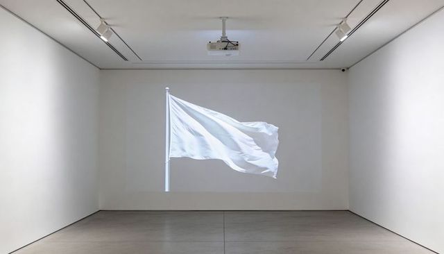 Projecting white flag waving across minimalist gallery wall with ceiling-mounted projector