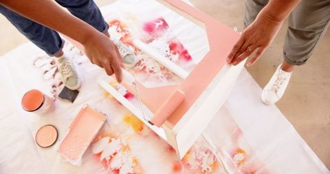 Hands revamping furniture with pink paint in diy project