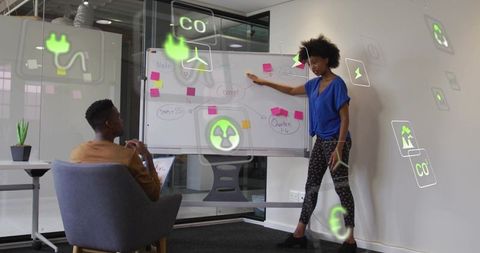 Presenter guiding brainstorming while holding tablet with AR sustainable energy icons