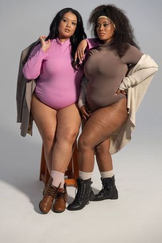 Posing together in bodysuits and coats showcasing plus-size diverse fashion with boots
