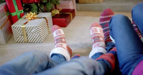 Family Relaxing with Warm Socks Near Christmas Tree and Gifts