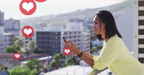 Woman Engaged with Social Media Hearts on City Balcony