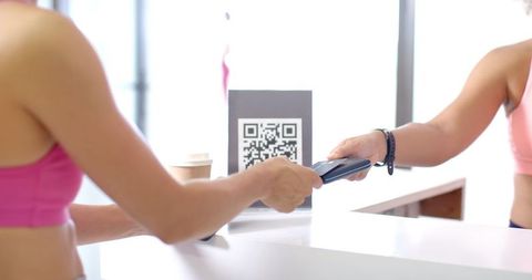 Women Using Smartphone for QR Code Payment in Gym Setting