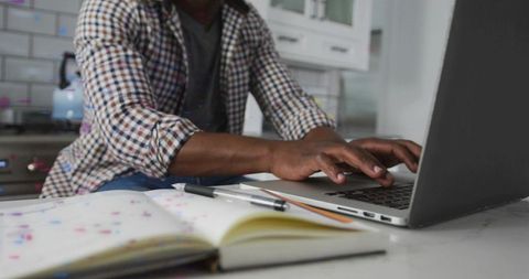 Man working on laptop in home office kitchen setting