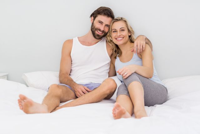 Portrait of romantic couple sitting on bed in bedroom