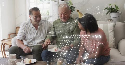 Multigenerational family celebrating birthday on couch cutting cake together at home