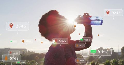 Silhouetted man drinking from water bottle on rooftop with augmented reality overlays