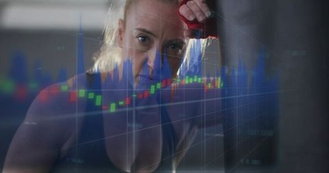 Determined female boxer training with red wraps overlaid with stock candlestick charts