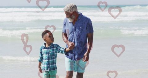 Grandfather and grandson enjoy beach walk with floating hearts