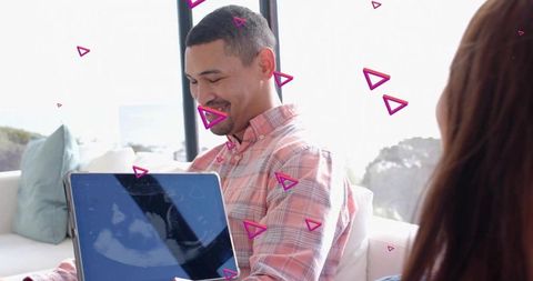 Smiling man holding laptop on sofa in bright living room with magenta overlays