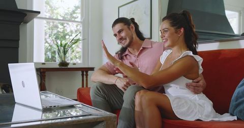 Joyful Couple Video Calling on Laptop in Cozy Living Room
