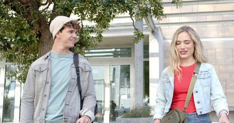 Young couple walking and smiling on urban campus walkway during bright daylight