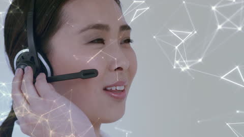 Smiling Asian Female Call Center using Headset with Digital Connections