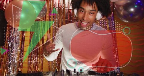 Mixing dj spinning party set with headphones, mixer decks and colorful tinsel backdrop