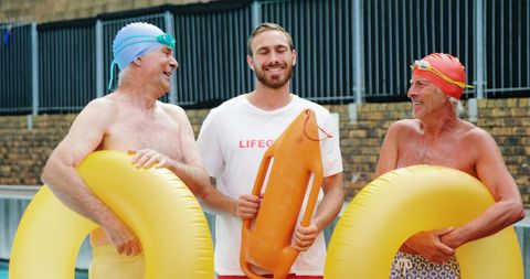 Swim coach interacting with seniors enjoying pool