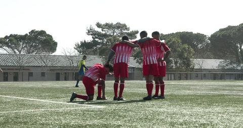 Soccer players in team hug pausing during match celebration
