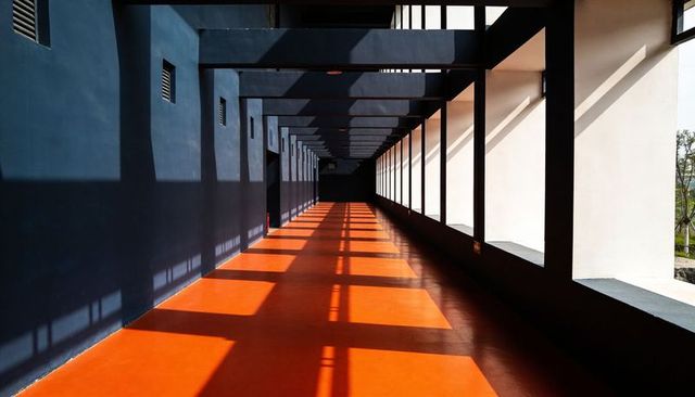 Sunlit Architectural Corridor Orange Floor Deep Blue Walls Strong Geometric Shadows