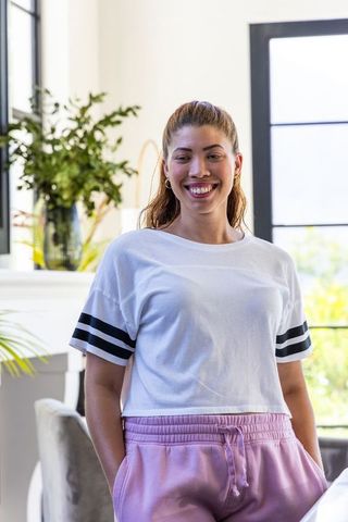 Smiling african american woman standing in bright home wearing pink joggers and white tee