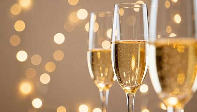 Elegant champagne flutes with rising bubbles and warm bokeh lights for celebration