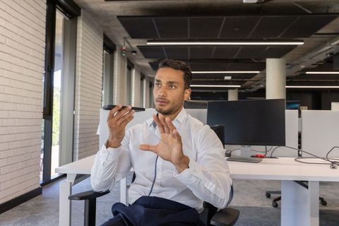 Businessman Using Smartphone for Hands-Free Call in Modern Office