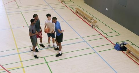 Multiracial male teammates huddling, preparing and motivating on indoor basketball court