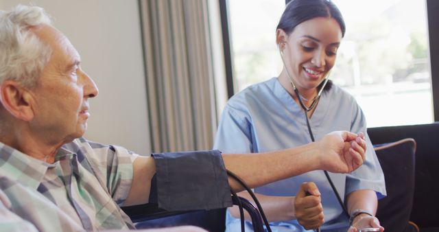 Image of happy biracial female doctor checking pressure to caucasian senior man. seniors health and nursing home lifestyle concept digitally generated image.