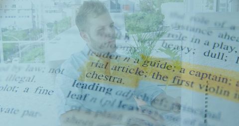 Man reading highlighted book on pale sofa by balcony plant, minimalist serene interior