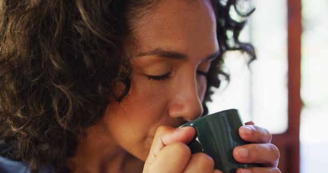 Close up of biracial woman drinking coffee at home. staying at home in self isolation in quarantine lockdown