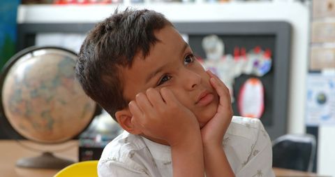 Thoughtful Schoolboy Contemplating at Desk in Classroom