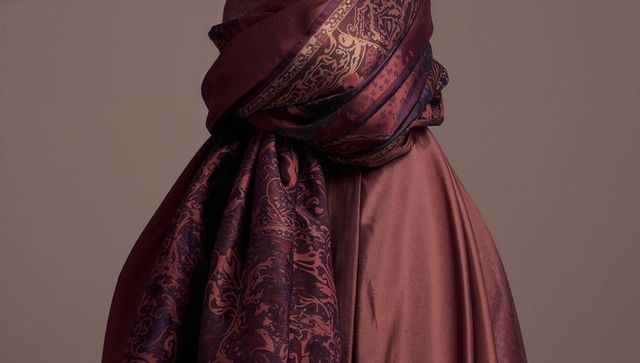 Female torso wearing satin mauve robe draping ornate burgundy paisley scarf, close-up