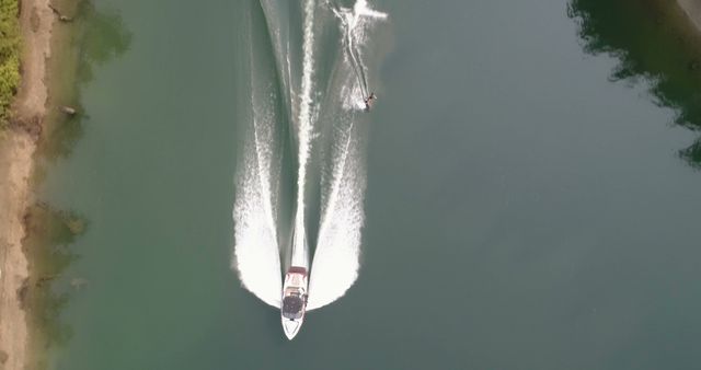 Aerial view of motorboat towing wakeboarder in serene lake - Download Free Stock Images Pikwizard.com