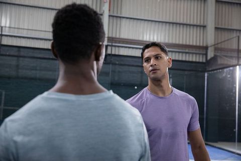 Two diverse men facing each other on indoor court preparing for intense training session