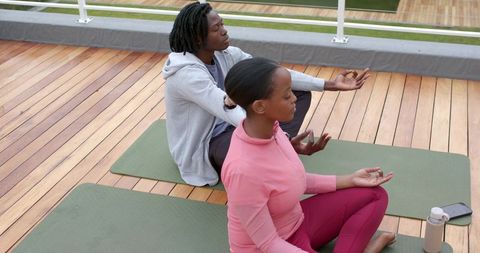 African American Couple Practicing Outdoor Meditation on Wooden Deck with Yoga Mats