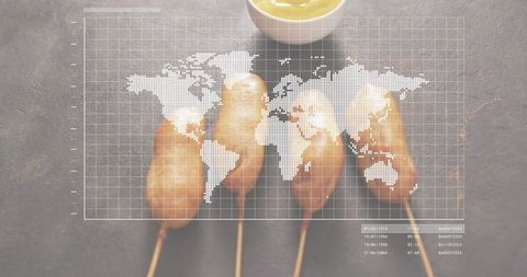 Corn dogs on skewers with mustard bowl and dotted world map overlay, flatlay food concept