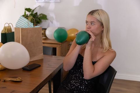 Woman preparing festive decor by inflating balloons