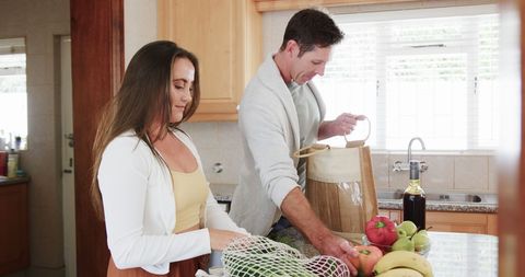 Couple Unpacking Groceries in Modern Sunny Kitchen Setting