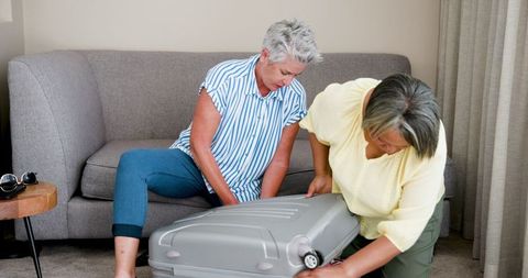 Senior Lesbian Couple Packing Suitcase for Vacation at Home