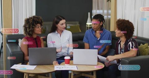 Female leader guiding diverse team in living room meeting with laptops and ar overlays