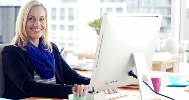 Smiling caucasian businesswoman sitting by desk and using computer in office - Download Free Stock Photos Pikwizard.com