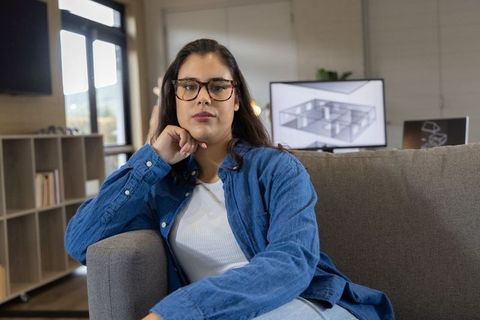 Designer analyzing 3d floor plan on monitor while sitting on sofa in home office