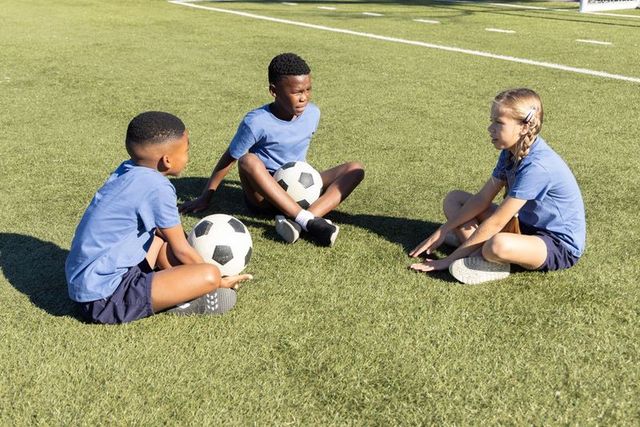 Youth soccer teammates sitting in circle on turf during casual practice