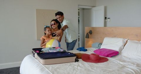 Family Enjoying Stay in Hotel Room Taking Selfie with Luggage
