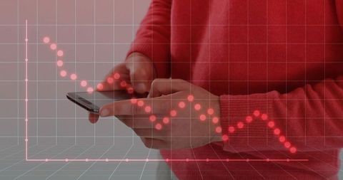 Hands holding smartphone with red declining financial graph overlay showing market downturn