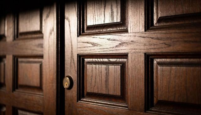 Dark-stained double wooden door with brass keyhole, raised panels and rich wood grain
