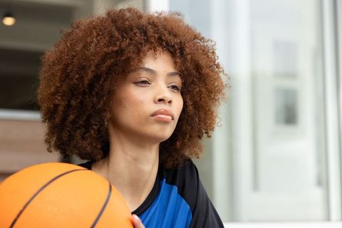 African american female athlete holding basketball looking determined close-up portrait