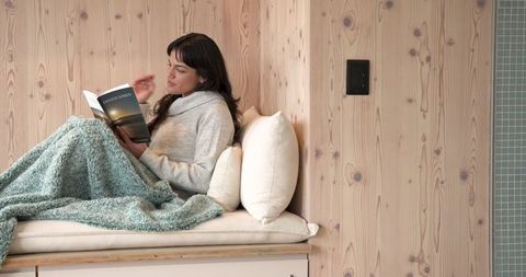 Woman enjoying quiet reading time under cozy knit blanket