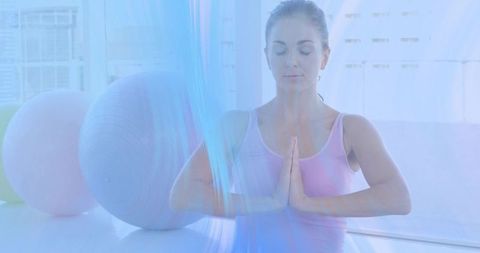 Woman Practicing Mindful Meditation and Yoga Near Stability Balls in Bright Wellness Studio