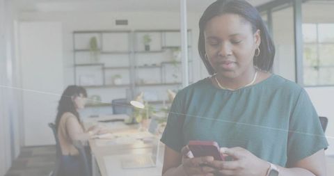 Professional woman tapping smartphone, reading message and smiling in modern office