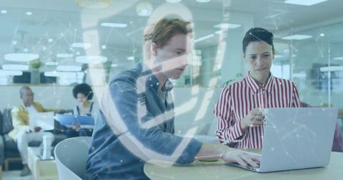 Colleagues reviewing report on laptop in modern open office