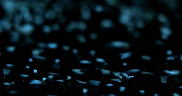 A dark image showcases scattered blue particles on a surface. The mysterious ambiance suggests a concept for technology or science fiction themes.